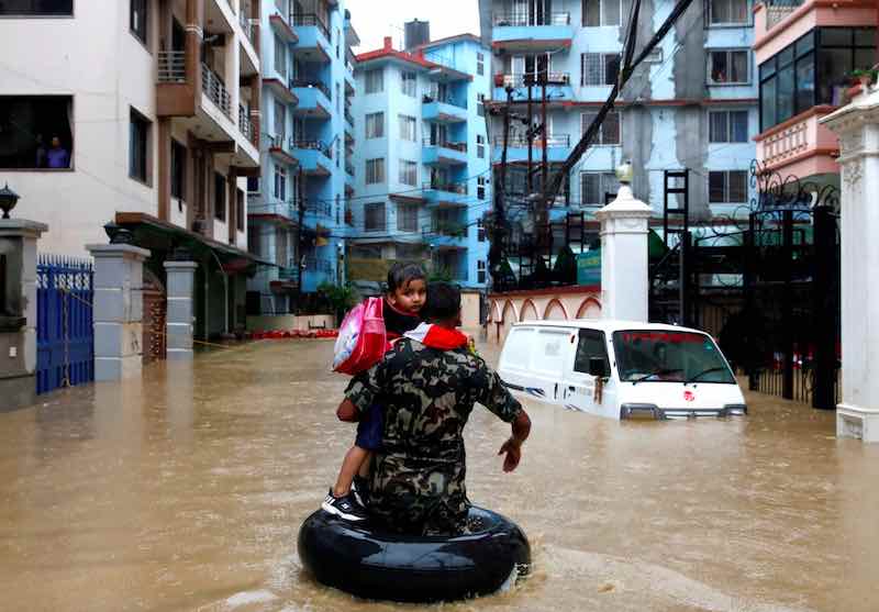 Un soldato che trasporta un bambino in una zona allagata di Kathmandu, in Nepal - meteoweek.com