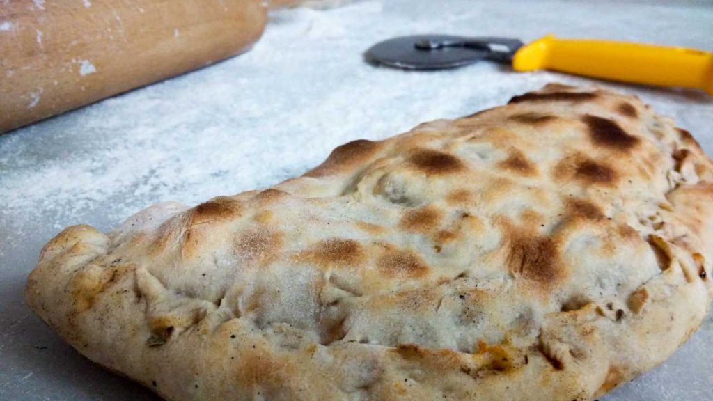 Calzone al prosciutto e formaggi, la ricetta golosa della pizza ripiena
