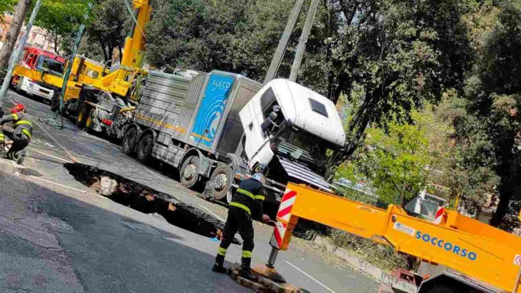 Roma, si apre una voragine nella strada: mezzo pesante sprofonda, l’intervento dei vigili del fuoco [VIDEO]